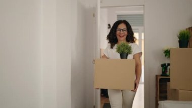 Orta yaşlı bir kadın yeni evine giderken kendine güvenen bir paket taşıyor.