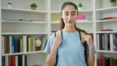 Genç, güzel, İspanyol bir kız öğrenci kütüphanede kendinden emin gülümsüyor.