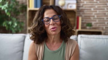 Middle age hispanic woman speaking to the camera