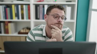Kütüphane üniversitesinde bilgisayar kullanan beyaz bir genç.