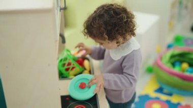 Sevimli İspanyol kız kreşte mutfakta oyun oynuyor.