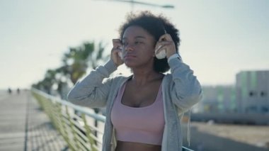 African american woman listening to music using stopwatch at street