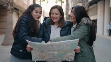 Anne ve kızları sokakta şehir haritasını kullanarak gülümsüyor.