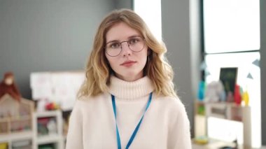 Young blonde woman preschool teacher smiling confident standing at kindergarten