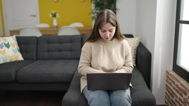 Młoda Blondynka Pomocą Laptopa Siedzi Kanapie Domu — Wideo stockowe
