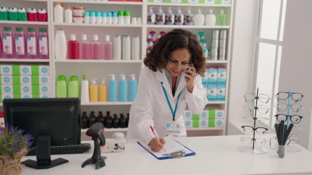 中年妇女药剂师在药店谈论智能手机文档写作 — 图库视频影像