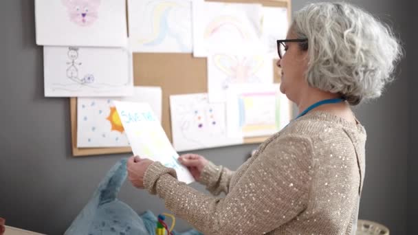 Mujer Mediana Edad Con Pelo Gris Maestro Preescolar Colgando Dibujar — Vídeo de stock