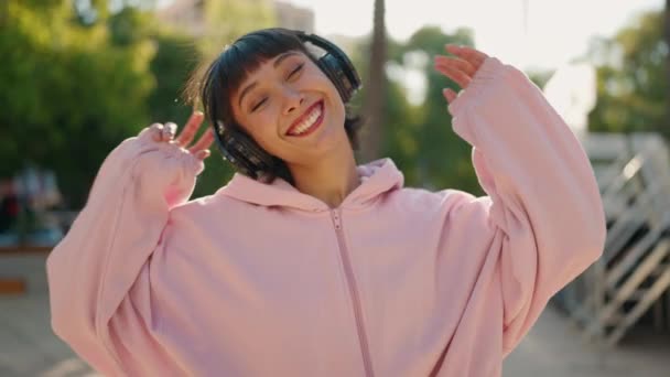 若いヒスパニック系の女性が自信を持って音楽を聴き 公園で踊る笑顔 — ストック動画