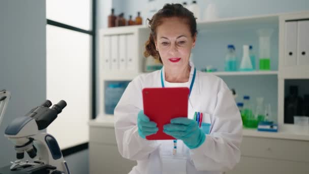中年妇女穿着科学家制服 在实验室使用触摸板 — 图库视频影像