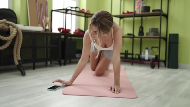Young Blonde Woman Training Legs Exercise Turning Smartphone Timer Sport — Stockvideo