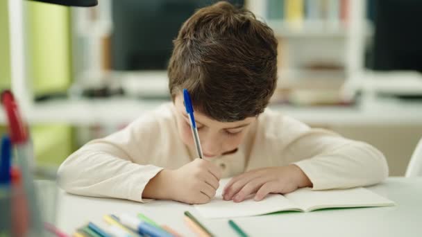 Liebenswerter Hispanischer Junge Schreibt Klassenzimmer Auf Notizbuch — Stockvideo