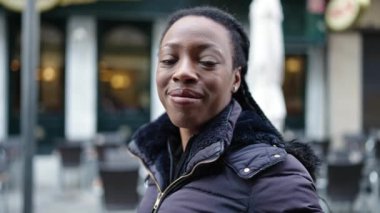 African american woman smiling confident standing at coffee shop terrace