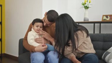 Çift ve oğul evdeki kanepede oturup birbirlerine sarılıyorlar.