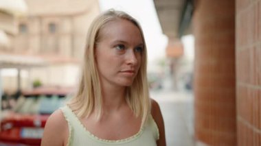 Young blonde woman smiling confident looking to the side at street