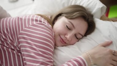 Genç sarışın kadın yatakta uzanıyor, yatak odasında uyuyor.