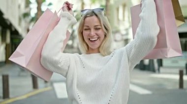 Gülümseyen genç sarışın kadın alışverişe çıkıyor.
