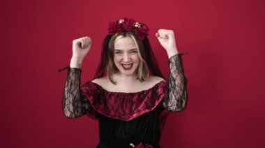 Katrina kostümü giyen genç sarışın bir kadın. İzole edilmiş kırmızı arka planda kazanan yüz ifadesi var.