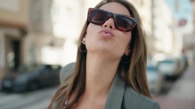 Young woman smiling confident kissing at street