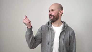 Genç kel adam gülümsüyor. Kendine güveni tam. İzole edilmiş beyaz arka planda parmak ucunda.