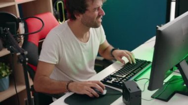 Genç İspanyol asıllı adam müzik stüdyosunda bilgisayar kullanarak video oyunu oynuyor.