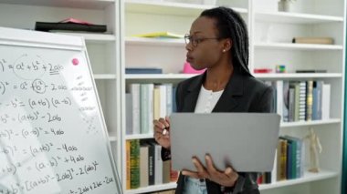 Üniversite sınıfında dizüstü bilgisayarla matematik dersi veren Afrikalı Amerikalı kadın öğretmen.