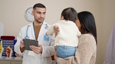 Çift ve oğlu klinikteki dokunmatik bloknotlara tıbbi danışmanlık yapıyorlar.