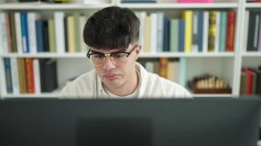 Genç İspanyol öğrenci kütüphanede bilgisayar kullanmaktan yoruldu.