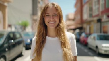 Genç sarışın kız sokakta kendine güvenerek yürüyor.