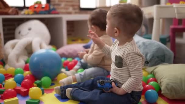Anaokulunun Zemininde Oturan Iki Küçük Bebek Top Arabayla Oynuyorlar — Stok video