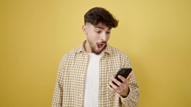 Młody Arabski Człowiek Pomocą Smartfona Gospodarstwa Dolarów Odizolowanym Żółtym Tle — Wideo stockowe