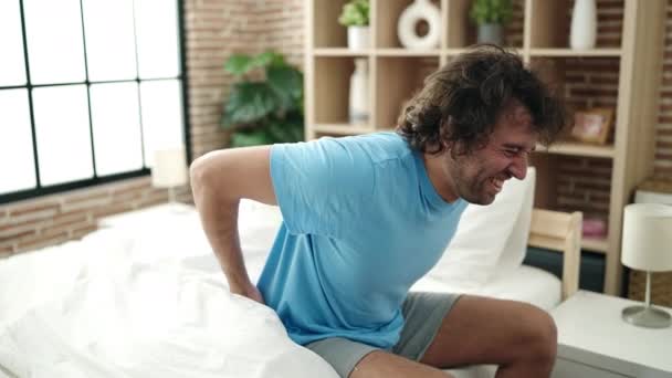 Jonge Spaanse Man Lijdt Aan Rugletsel Zittend Bed Slaapkamer — Stockvideo