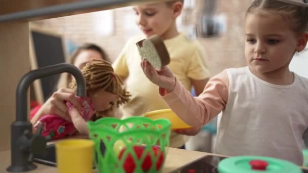 幼儿园里的老师 男孩和女孩一起玩游乐厨房 — 图库视频影像