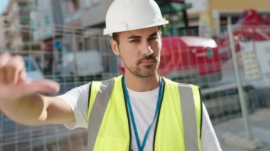 Genç İspanyol mimar kendinden emin gülümsüyor. Sokakta baş parmaklarıyla iyi bir hareket yapıyor.