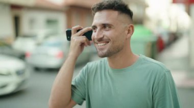 Genç İspanyol adam gülümsüyor. Caddedeki akıllı telefondan kendine güvenen bir sesli mesaj dinliyor.