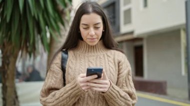 Genç ve güzel İspanyol kadın akıllı telefon kullanıyor. Sokakta ciddi bir ifadesi var.