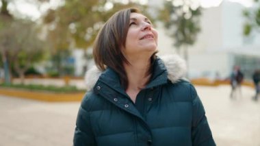 Middle age woman smiling confident looking to the sky at park