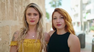 İki kadın sokakta birbirine sarılarak gülümsüyor.