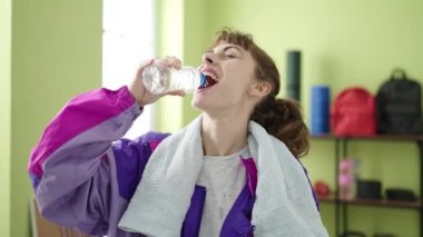 Young caucasian woman doing exercise drinking water at sport center