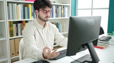 Young hispanic man student doing yoga exercise at library university