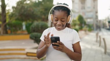 Afrikalı Amerikalı kadın parkta müzik dinliyor ve dans ediyor.