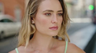 Young blonde woman smiling confident combing hair with hand at street