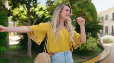 Genç bayan parkta dans ederken kendinden emin gülümsüyor.