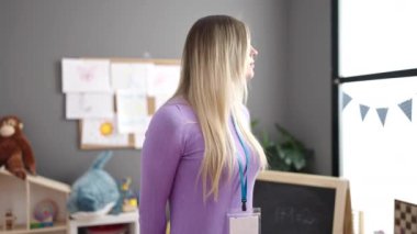 Young blonde woman preschool teacher smiling confident standing at kindergarten