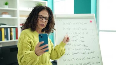 Orta yaşlı İspanyol kadın öğretmen kütüphane üniversitesinde online matematik egzersizi anlatıyor.