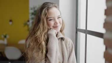Young beautiful hispanic woman smiling confident leaning on window at home