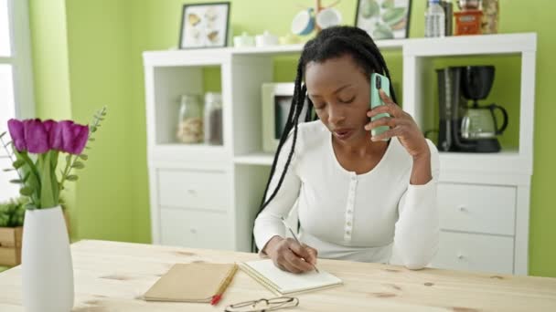 Afrikaans Amerikaanse Vrouw Praten Smartphone Schrijven Notebook Thuis — Stockvideo
