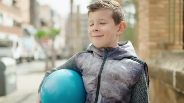 Ξανθό Παιδί Χαμογελά Αυτοπεποίθηση Κρατώντας Μπάλα Στο Δρόμο — Αρχείο Βίντεο