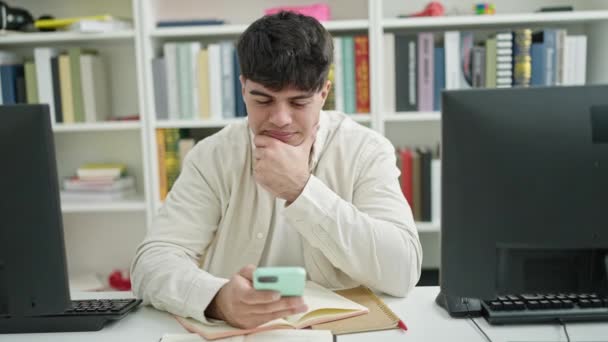 Young Hispanic Man Student Using Smartphone Sitting Table Library University — Vídeo de Stock