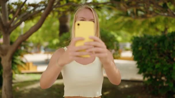 Genç Sarışın Kadın Kendinden Emin Gülümsüyor Parktaki Akıllı Telefonun Yanında — Stok video