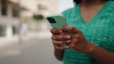 Sokakta akıllı telefon kullanan Afrikalı Amerikalı bir kadın.